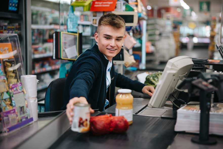 Trabajador de primera línea desempeñando su actividad como cajero en un supermercado